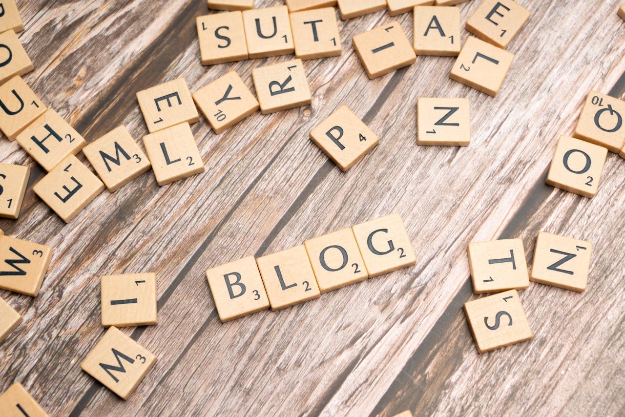 hero-img-02 Scattered wooden letter tiles spelling 'Blog' on a rustic wood background.