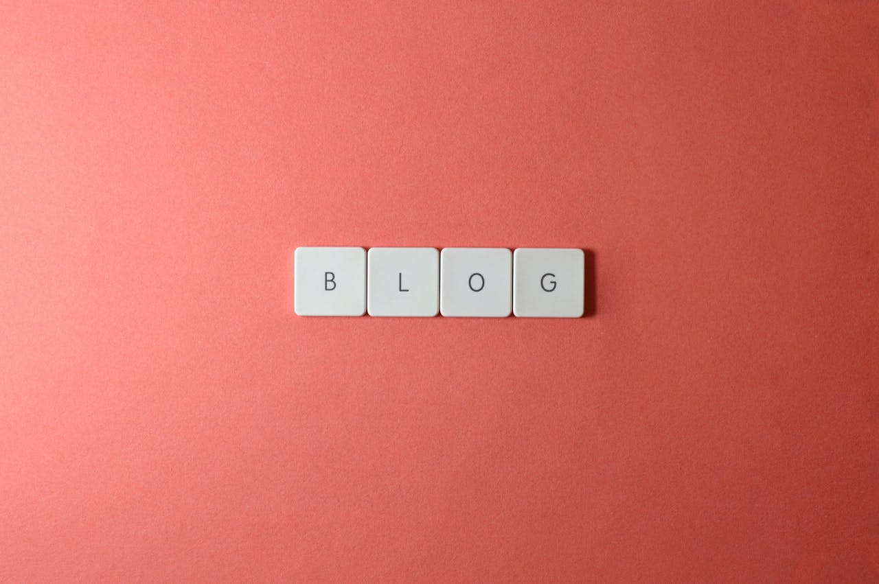 hero-img-01 A minimalist image of keyboard keys spelling 'BLOG' on a coral background.