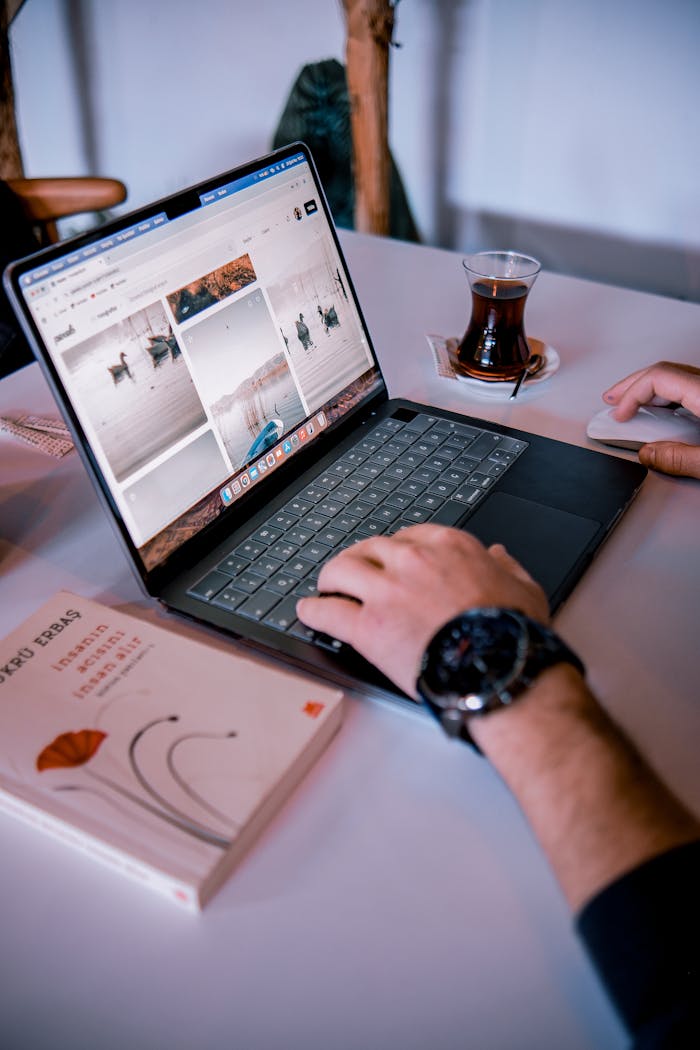 contact-img Person using laptop with a tea glass nearby in a cozy indoor setting.