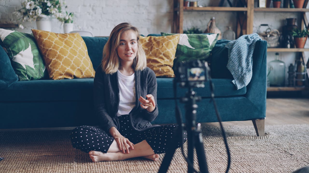 services-03 A young woman creating a vlog from her cozy living room with a camera setup.