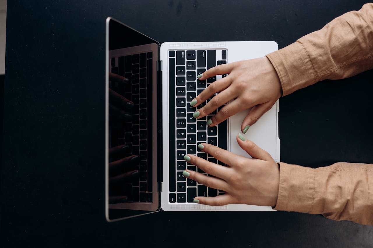 gallery-2 Top view of hands typing on a laptop keyboard, showcasing modern technology use.