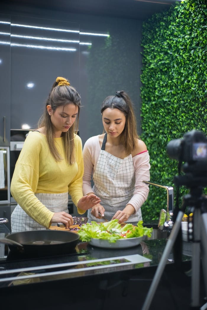 gallery-6 Two women preparing a meal in a stylish kitchen with green accents.