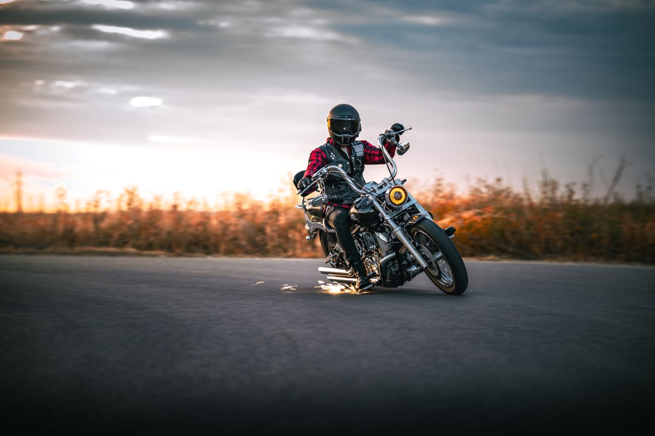 services-04 Motorcyclist in black helmet leans mid-turn on open road at sunset.