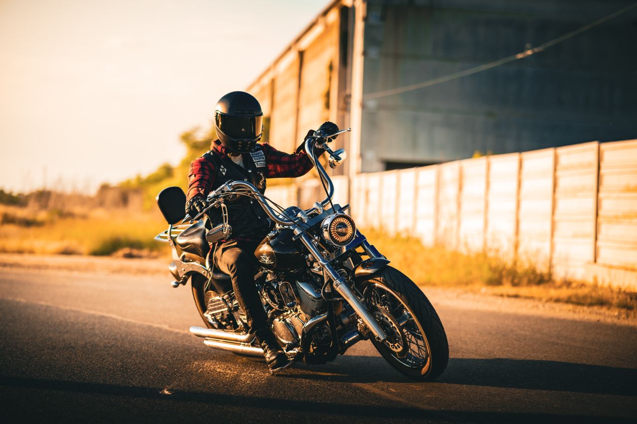 services-03 Biker rides a cruiser motorcycle on an open road during sunset, showcasing adventure and freedom.