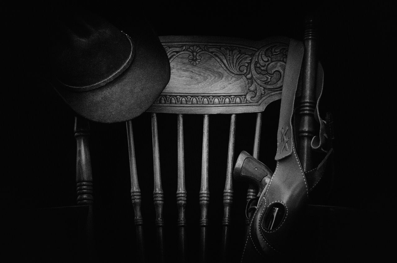 The Art of Drawing Readers In: Your attractive post title goes here A classic western-themed black and white still life featuring a hat, wooden chair, and gun.